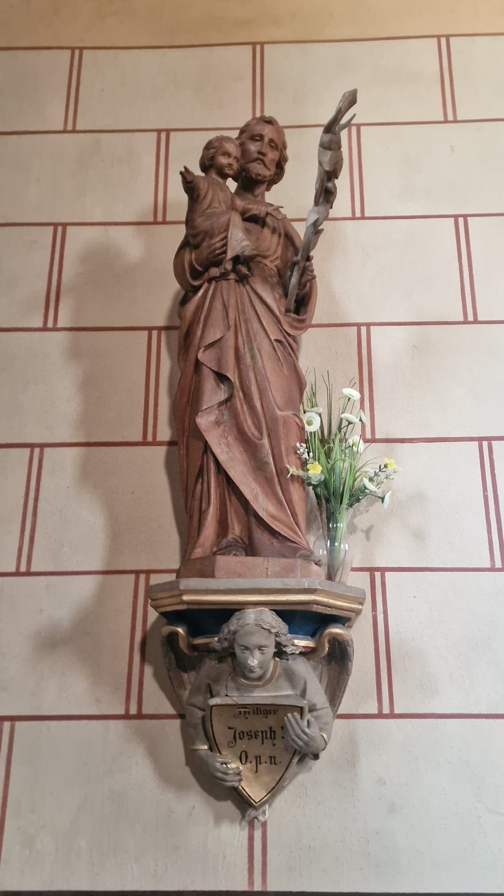 Der heilige Josef mit dem Kind, auf einer Konsole mit einem Engel. Auf dem Schild: „Heiliger Joseph! O. p. n.“, kurz für ora pro nobis, bitte für uns.